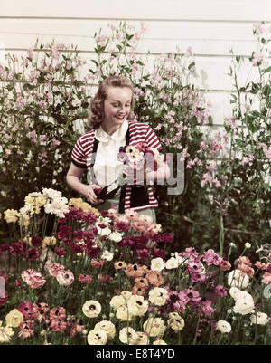 Années 1940 Années 1950 SMILING WOMAN IN GARDEN Picking Flowers Banque D'Images