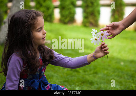 La main de l'enfant donnant des fleurs à son amie Banque D'Images