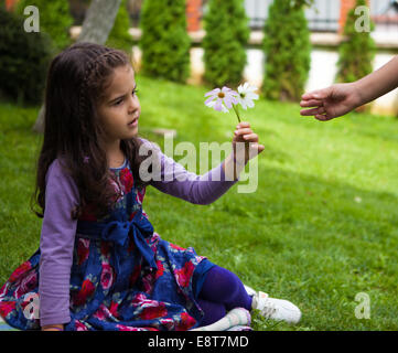 La main de l'enfant donnant des fleurs à son amie Banque D'Images