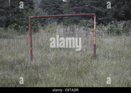 Ancien objectif football métallique ruiné dans l'herbe haute Banque D'Images