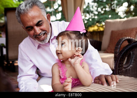 Grand-père assis avec sa petite-fille at Birthday party Banque D'Images