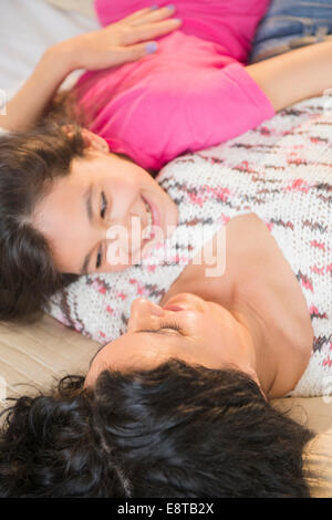 Hispanic mother and daughter relaxing together on bed Banque D'Images