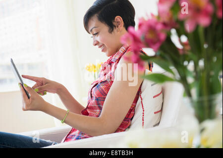 Mixed Race woman sitting on sofa Banque D'Images