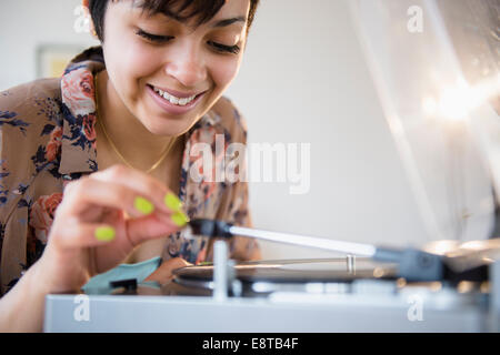 Smiling mixed race woman playing vinyl record Banque D'Images