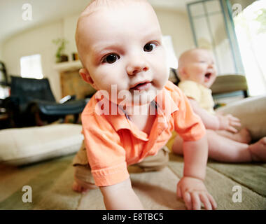 Caucasian baby crawling sur le plancher du salon Banque D'Images