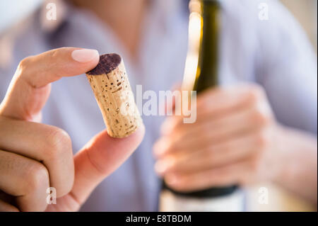 Close up of mixed race man holding wine cork Banque D'Images