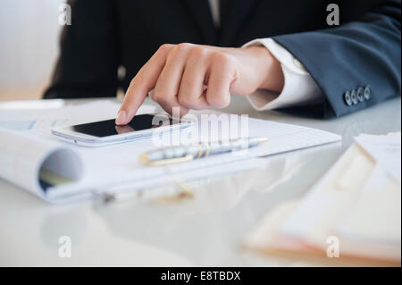 Close up of mixed race businessman using cell phone at desk Banque D'Images