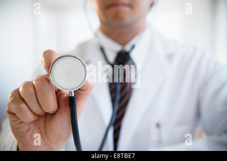 Close up of mixed race doctor holding stethoscope Banque D'Images