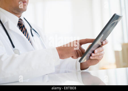 Close up of mixed race doctor using digital tablet Banque D'Images