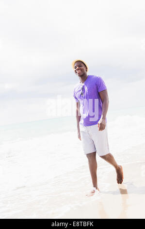 Mixed Race man walking on beach Banque D'Images