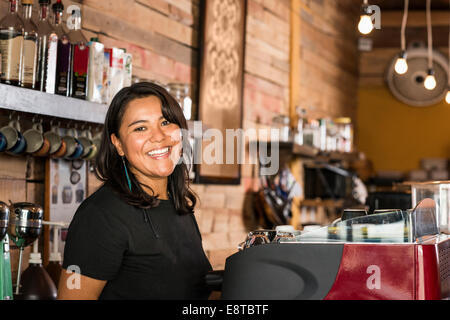 Smiling Hispanic woman working in coffee shop Banque D'Images