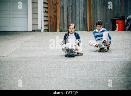 Mixed Race frère et sœur équitation skateboards en entrée Banque D'Images