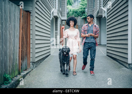 Mixed Race woman walking dog en banlieue de complexe Banque D'Images