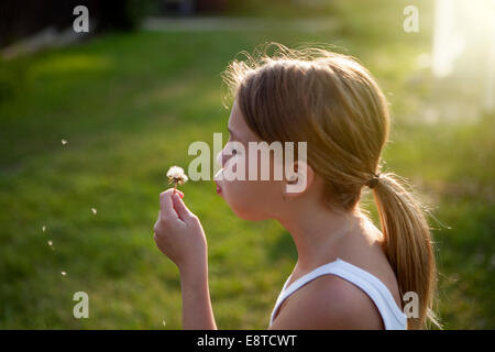 Young Girl blowing dandelion seeds off Banque D'Images