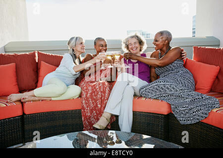 Women toasting each other with wine on urban rooftop Banque D'Images