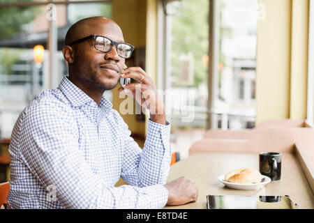 Black man talking on cell phone in coffee shop Banque D'Images