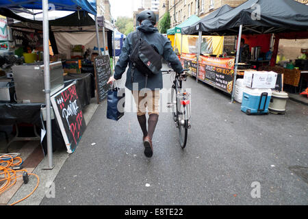 Barbican, Londres UK. 14 octobre 2014. Sur un matin près de la barbacane à sec dans la ville de Londres un cycliste portant plus 4s fait sa façon de travailler par Whitecross Street Market en tant que vendeurs mis en place leurs stands pour le déjeuner. Nuageux et brumeux les conditions météorologiques peuvent lever dans l'après-midi et des périodes de sécheresse continuent jusqu'à mercredi après-midi. Credit : Kathy deWitt/Alamy Live News Banque D'Images