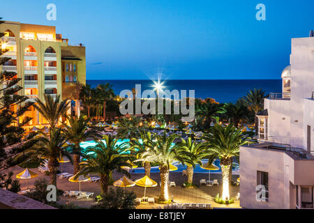 Crépuscule sur la piscine d'un hôtel 5 étoiles près de Port el Kantoui dans Tunsia avec la Méditerranée au-delà. Banque D'Images