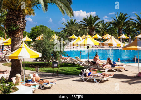Les vacanciers bronzer autour de la piscine d'un hôtel 5 étoiles près de Port el Kantoui dans Tunsia. Banque D'Images