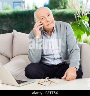 Senior man using smartphone au foyer de porche Banque D'Images