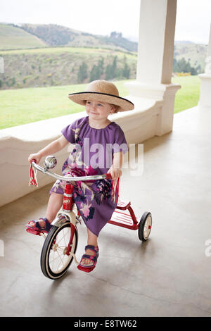 Joli trois ans dans un chapeau sur un tricycle