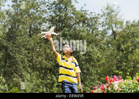 1 Indian Kid Flying Airplane in Park Banque D'Images