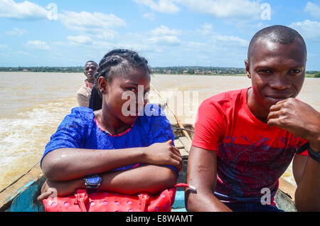 Un couple sur un petit bateau en bois traversant le fleuve Niger entre Al-Qaida et Agenebode, Nigéria Banque D'Images