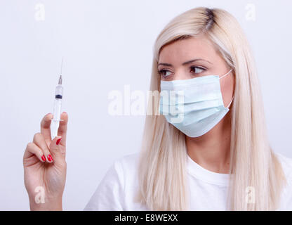 Femme médecin ou infirmière en masque médical holding syringe avec injection Banque D'Images