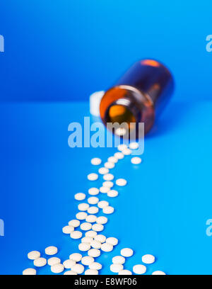 Prescription Pills déversant à partir de la bouteille sur le compteur bleu Banque D'Images
