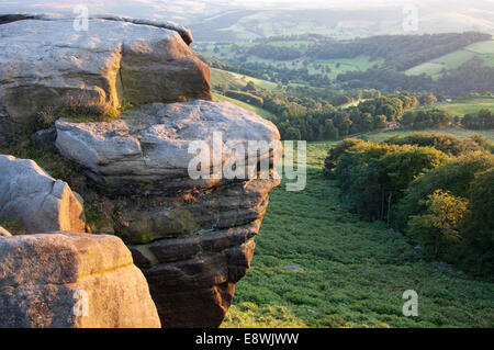 Vue de haut de Stanage edge, Peak District, l'Angleterre. Coucher du soleil chaud glow sur les rochers. Banque D'Images