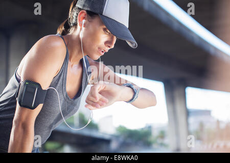 Woman looking at watch après l'exercice, on city street Banque D'Images