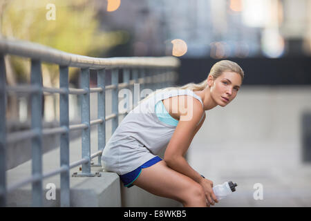 Femme se reposant après l'exercice on city street Banque D'Images