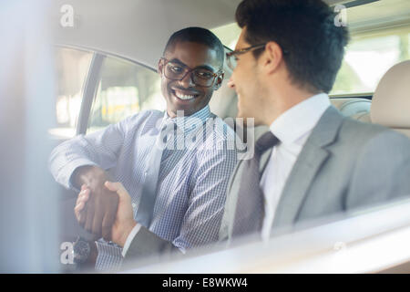 Smiling businessmen shaking hands in car Banque D'Images