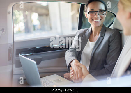 Businesswomen shaking hands in car Banque D'Images