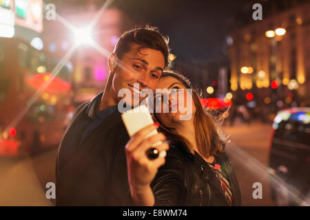 Couple taking photo avec téléphone cellulaire pendant la nuit Banque D'Images