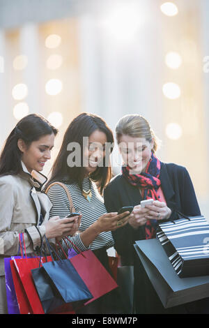 Les femmes utilisant des téléphones portables on city street Banque D'Images