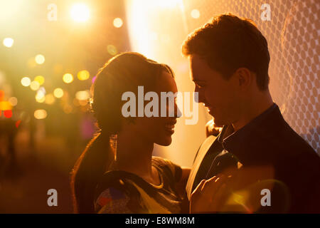 Couple hugging on city street at night Banque D'Images