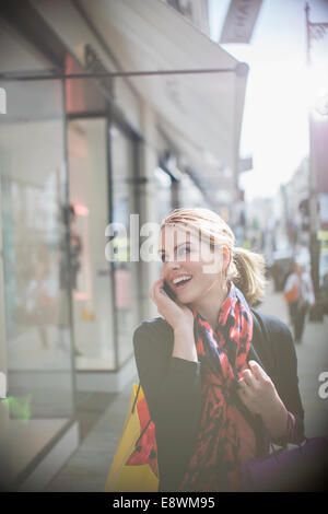 Woman talking on cell phone tout en descendant la rue de la ville Banque D'Images