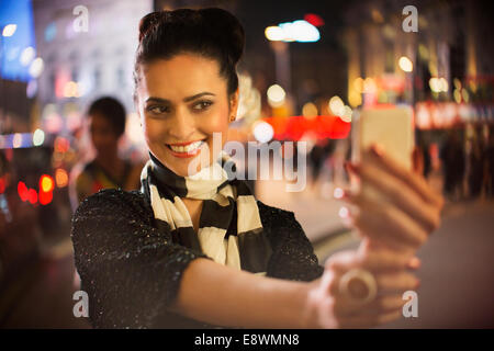 Woman taking photo using cell phone at night Banque D'Images