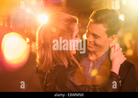 Couple hugging on city street at night Banque D'Images