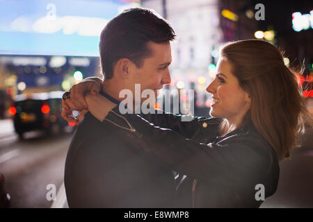 Couple hugging on city street at night Banque D'Images