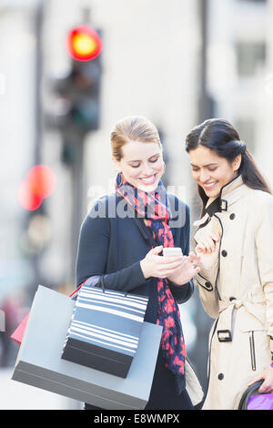 Les femmes à la recherche de cell phone on city street Banque D'Images