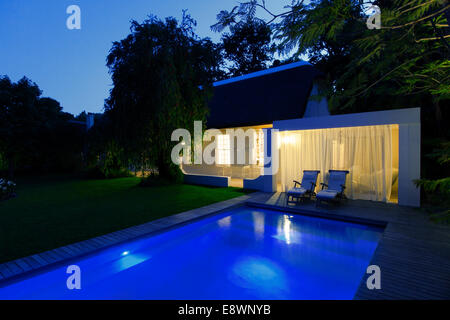 Maison moderne avec vue sur la piscine éclairée la nuit Banque D'Images