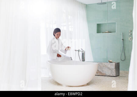 Woman running baignoire dans salle de bains moderne Banque D'Images