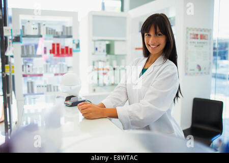 Pharmacist smiling behind counter en pharmacie Banque D'Images