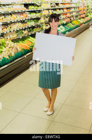 Greffier holding blank card dans la section des fruits et légumes épicerie Banque D'Images