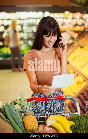 Femme parlant au téléphone cellulaire en shopping in grocery store Banque D'Images