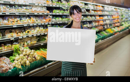 Greffier holding blank card dans la section des fruits et légumes épicerie Banque D'Images