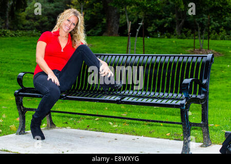 Modèle féminin en casual clothing sitting on bench Banque D'Images