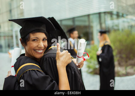 Les élèves en cap and gown hugging Banque D'Images